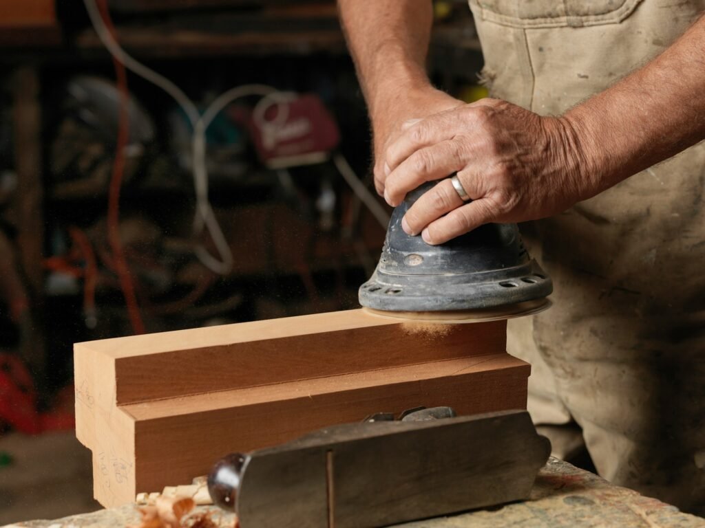 Boat builder sanding wood in workshop